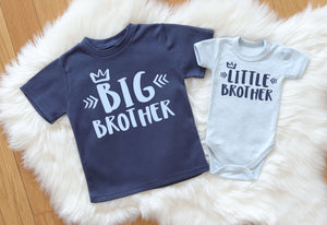Flatlay image showcasing the Big Brother & Little Brother matching set. Features a dark blue short sleeve t-shirt with light blue 'Big Brother' print, paired with a light blue short sleeve baby bodysuit with dark blue 'Little Brother' print. The set is made from 100% soft and comfortable cotton.